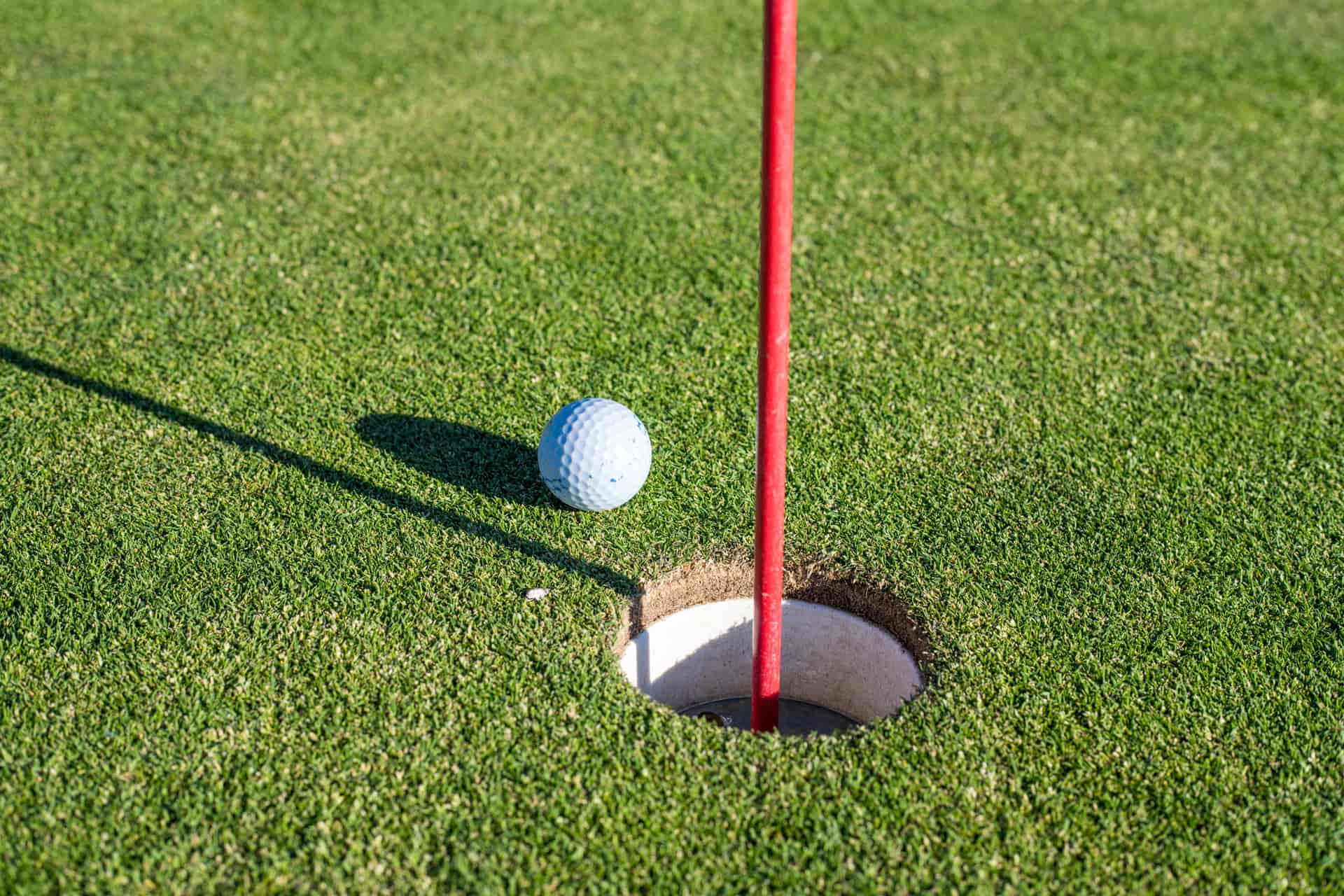 A putting green with the hole and flagstick in low winter light