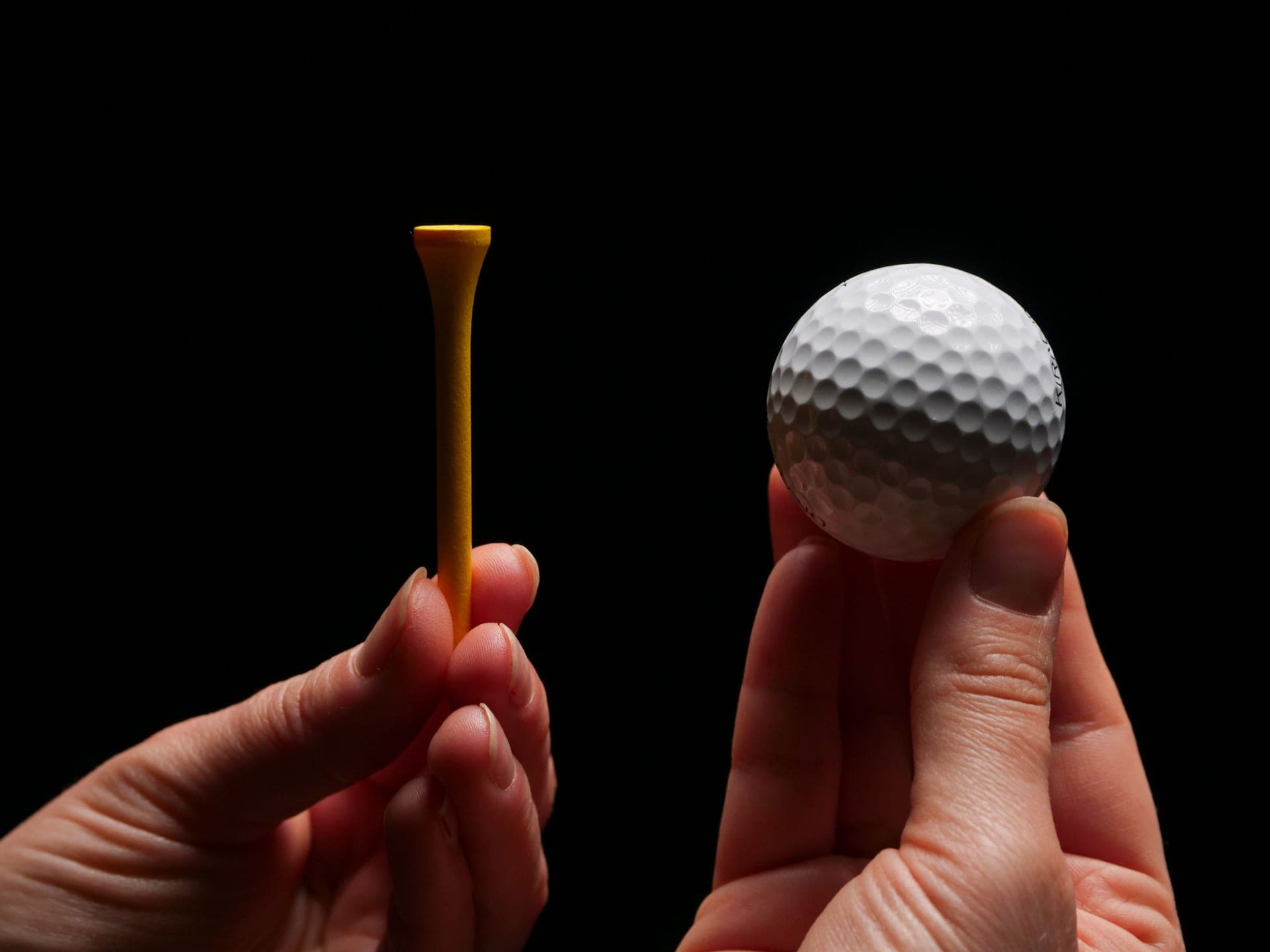 A golf ball on a tee in hard, low afternoon light