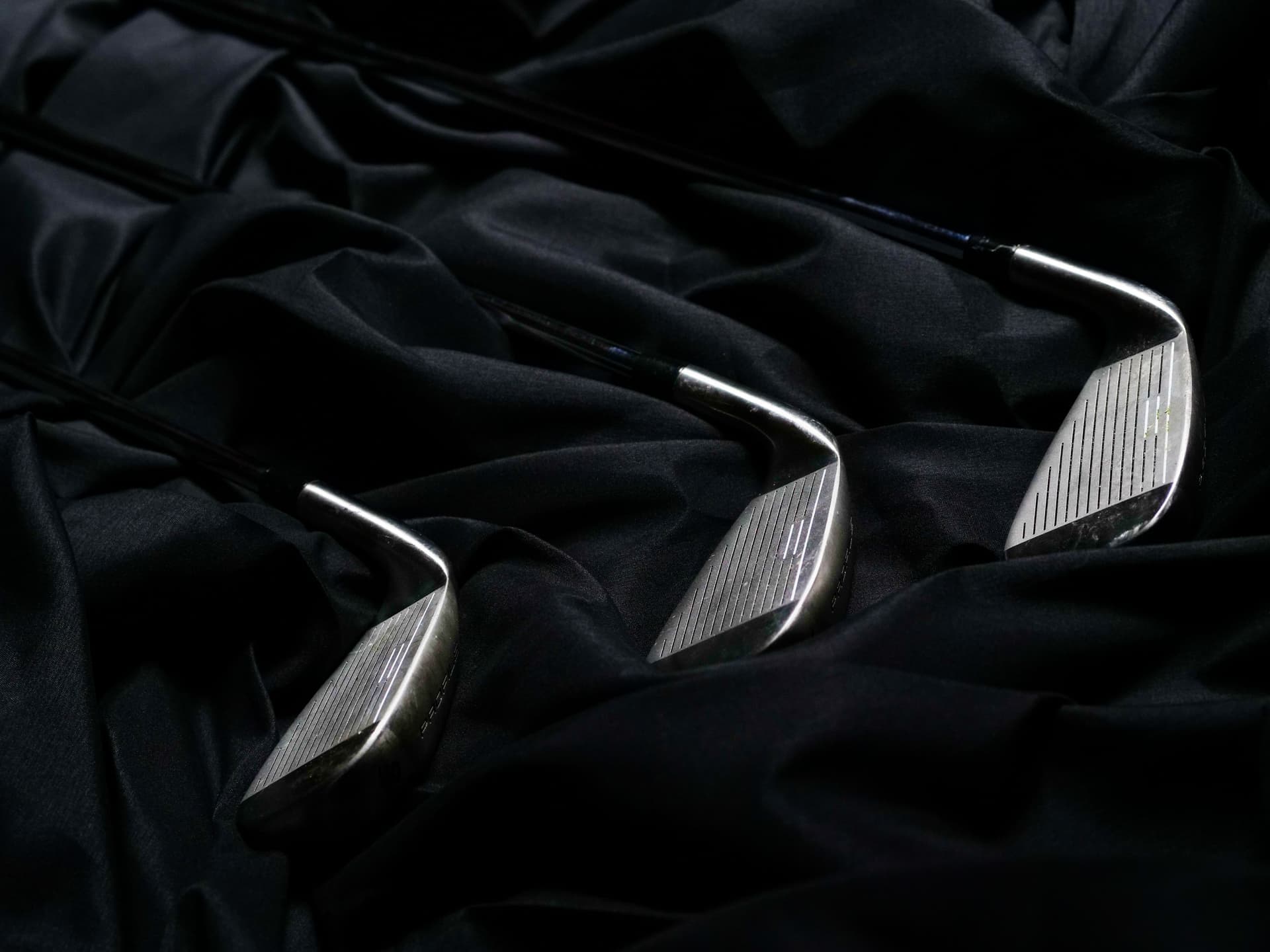 Golf irons lined up against a dark background
