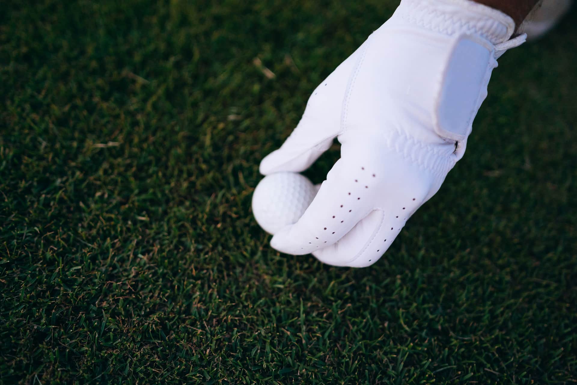 A golf glove and ball resting on grass