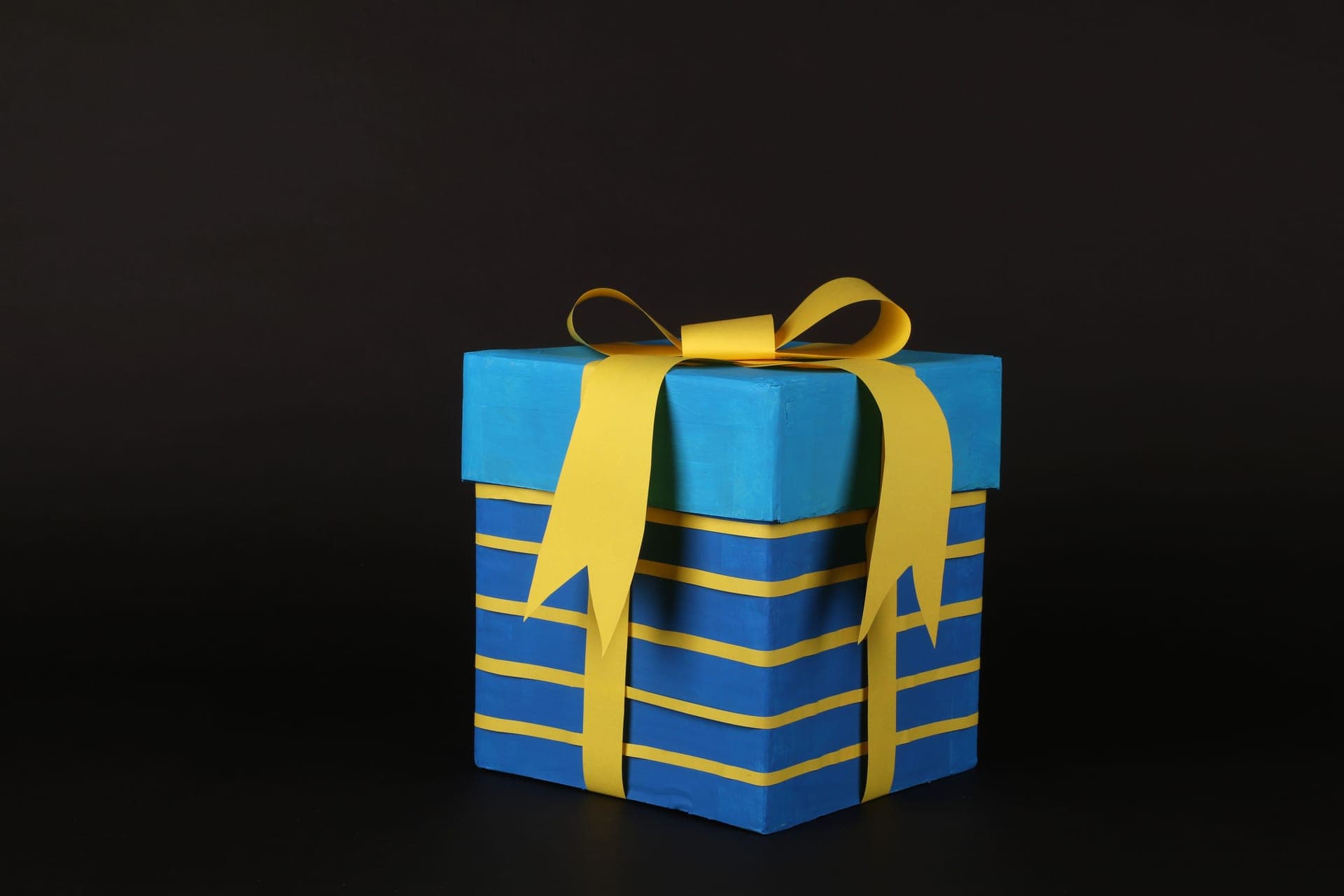 A wrapped gift box beside golf balls on a plain background